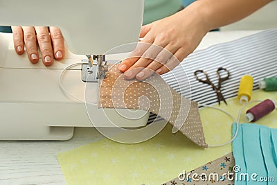 Woman sewing cloth mask with machine at table, closeup. Personal protective equipment during COVID-19 pandemic Stock Photo