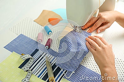 Woman sewing cloth mask with machine at table, closeup. Personal protective equipment during COVID-19 pandemic Stock Photo