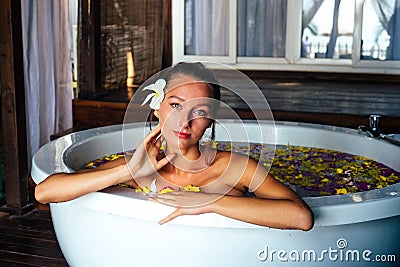 Woman sexy brunette relaxing in bath with tropical flowers outdoor at luxury hotel resort. Organic skin health care Stock Photo