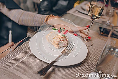 Woman sexy hands of serving strawberry piece of cheesecake with caramel near a glass champagne, jam and Napoleon in a restaurant Stock Photo