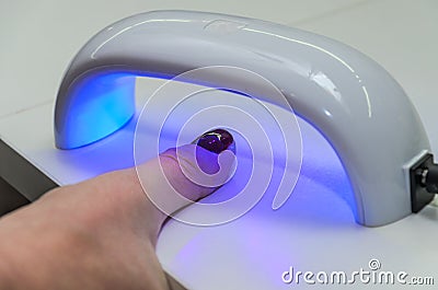 Woman shines with ultraviolet lamp on nails after manicure for nail polish to harden Stock Photo