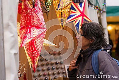 Woman Shopper Browsing at Bright Artisanal Starlight Lanterns at a Christmas Market. Editorial Stock Photo