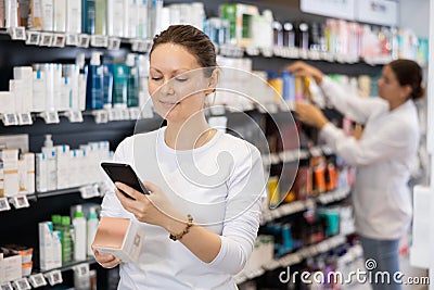 Woman shopper scanning a barcode on a cosmetics package with her phone. Searching for information via Internet Stock Photo