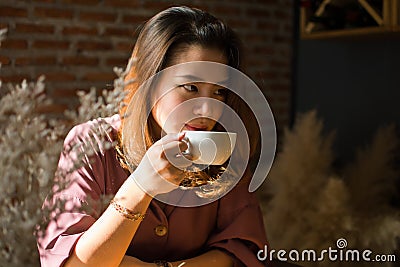 A pretty woman is looking for something while drinking coffee Stock Photo