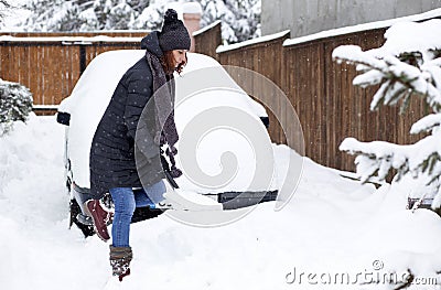 woman with shovel cleaning snow aeound car. Winter shoveling. Removing snow after blizzard Stock Photo