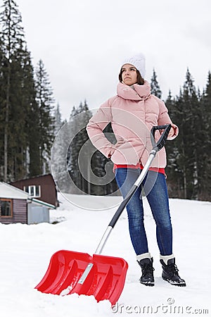 Woman with shovel for cleaning snow near house Stock Photo
