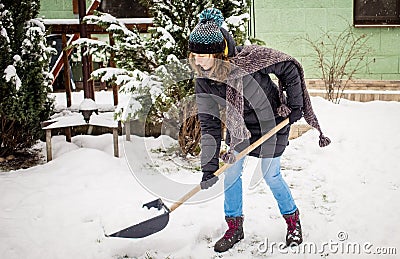 woman with shovel cleaning snow. Winter shoveling. Removing snow after blizzard Stock Photo