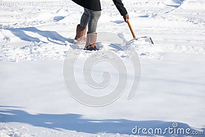 Woman shovelling snow to clear her driveway after winter storm Stock Photo