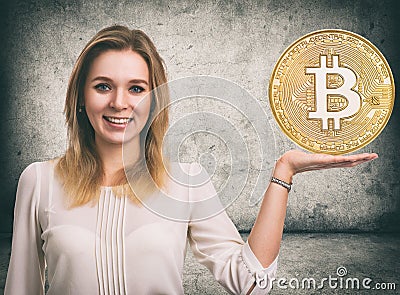 Woman showing Golden Bitcoin coin. Cryptocurrency Stock Photo