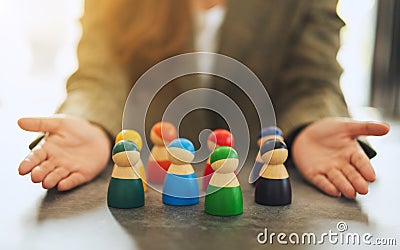 A woman showing a group of different colors wooden people toy in hands for diversity and business concept Stock Photo