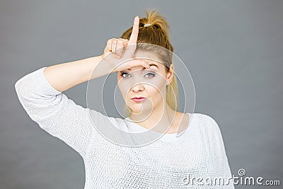 Woman showing loser gesture with L on forehead Stock Photo