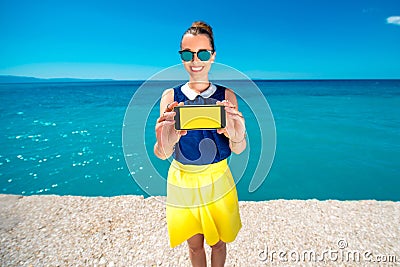 Woman showing phone screen near the sea Stock Photo