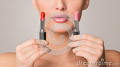 Cropped of Woman Holding Two Lipsticks, Grey Background Stock Photo