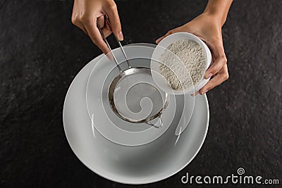 Woman sieving flour into the bowl Stock Photo