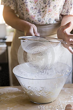 Woman sieving flour into a bowl Stock Photo