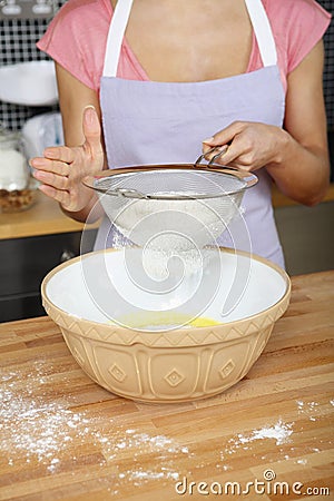 Woman sieving flour into mixing bowl. Conceptual image Stock Photo