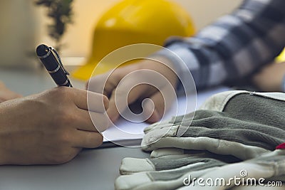 Woman signing construction contract with contractor. Yellow helm Stock Photo