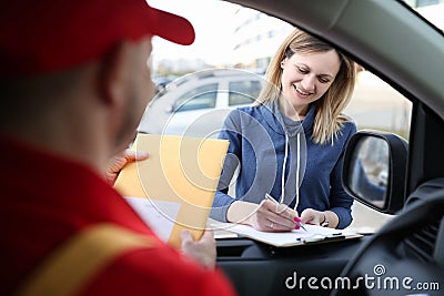 Woman signing documents and receiving yellow postal envelope Stock Photo