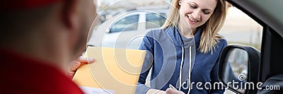 Woman signing documents and receiving yellow postal envelope Stock Photo