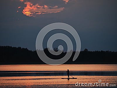 Woman silhouette on paddle board in the lake Stock Photo