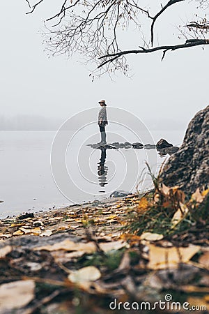 Woman silhouette on the river bank in the morning fog Stock Photo