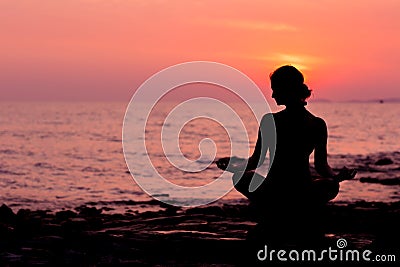 Woman silhouette sitting in lotus position on sea background back lit Stock Photo