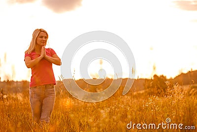 Woman silhouette waiting for summer sun on meadow Stock Photo