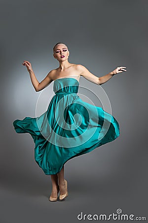 Woman in silk dress waving on wind. Flying and fluttering gown cloth over gray background Stock Photo