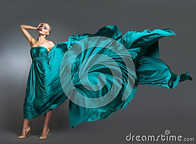 Woman in silk dress waving on wind. Flying and fluttering gown cloth over gray background Stock Photo