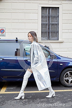 Woman with silver transparent raincoat and white boots walking before Boss fashion show, Milan Editorial Stock Photo