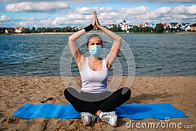 Woman in singular mask do yoga on the beach Stock Photo