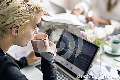 Woman Sipping Coffee while Working on Laptop Stock Photo