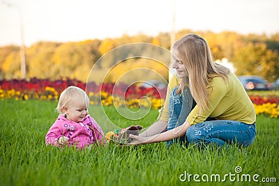 Woman sit on green grass near beds of flowers Stock Photo