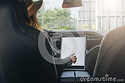 Woman sits behind wheel in car and uses electronic dashboard. Girl traveler looking for way through navigation system. Stock Photo