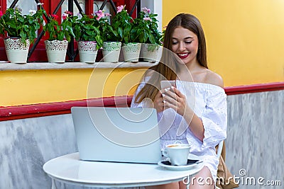 Woman sits in a brasserie and works on laptop and smartphone Stock Photo