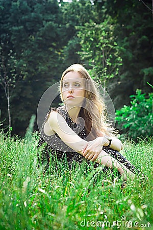 Woman sits at a forest's meadow Stock Photo
