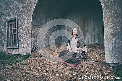 A woman sits on the hay in a vintage town in medieval Europe Stock Photo