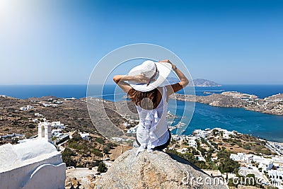 Woman sits on a rock high over the village of Ios island Stock Photo