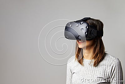 Woman Sits On Sofa At Home Wearing Virtual Reality Headset Stock Photo