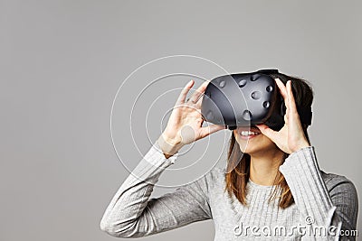 Woman Sits On Sofa At Home Wearing Virtual Reality Headset Stock Photo