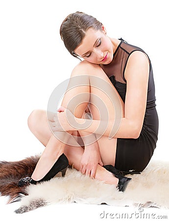 Woman sits on soft fluffy sheep skin Stock Photo