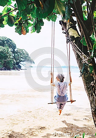 Woman sits on the tree swing on the Weligama sandy beach coast Stock Photo