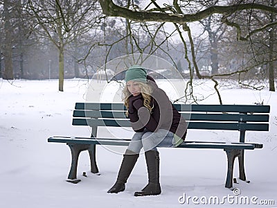 Woman sitting alone on park bench in winter Stock Photo