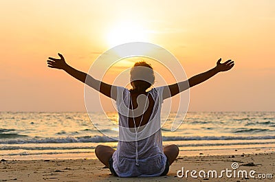 woman is sitting on beach at sunrise Stock Photo