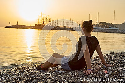 Woman sitting on the beach and watching the sunset Stock Photo