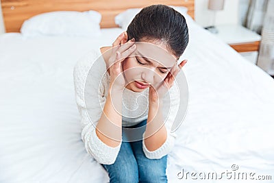 Woman sitting on the bed and having head pain Stock Photo