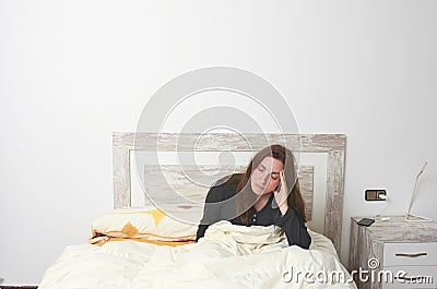 Woman sitting on bed irritated when they hear the alarm clock. E Stock Photo