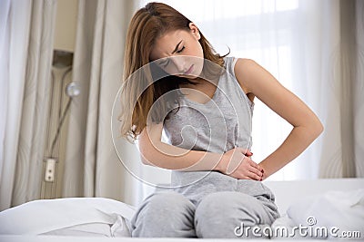 Woman sitting on the bed with pain Stock Photo