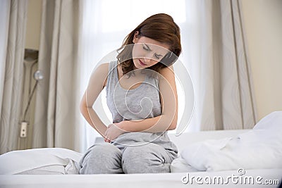 Woman sitting on the bed with pain Stock Photo