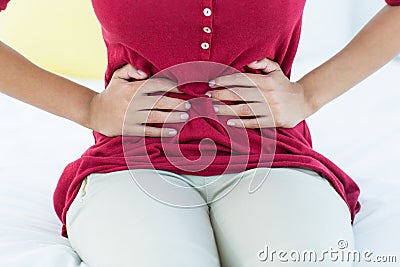 Woman sitting on bed with stomach pain Stock Photo